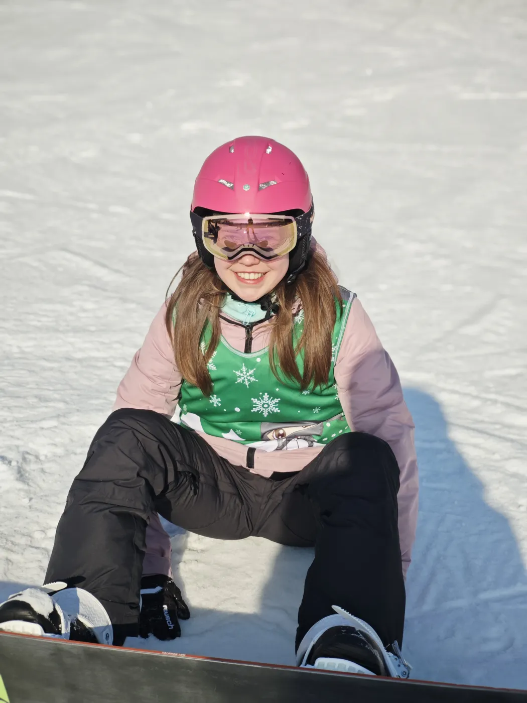Dziewczynka odpoczywająca na śniegu z deską snowboardową
