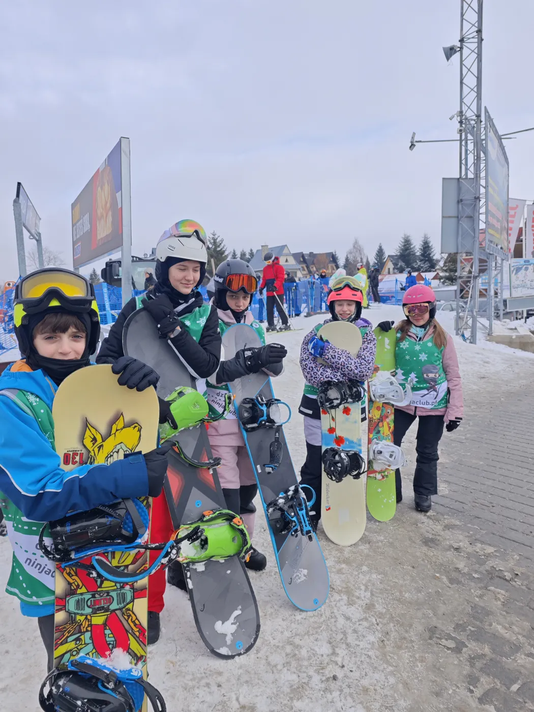 Grupa uczestników obozu z deskami snowboardowymi przy stacji
